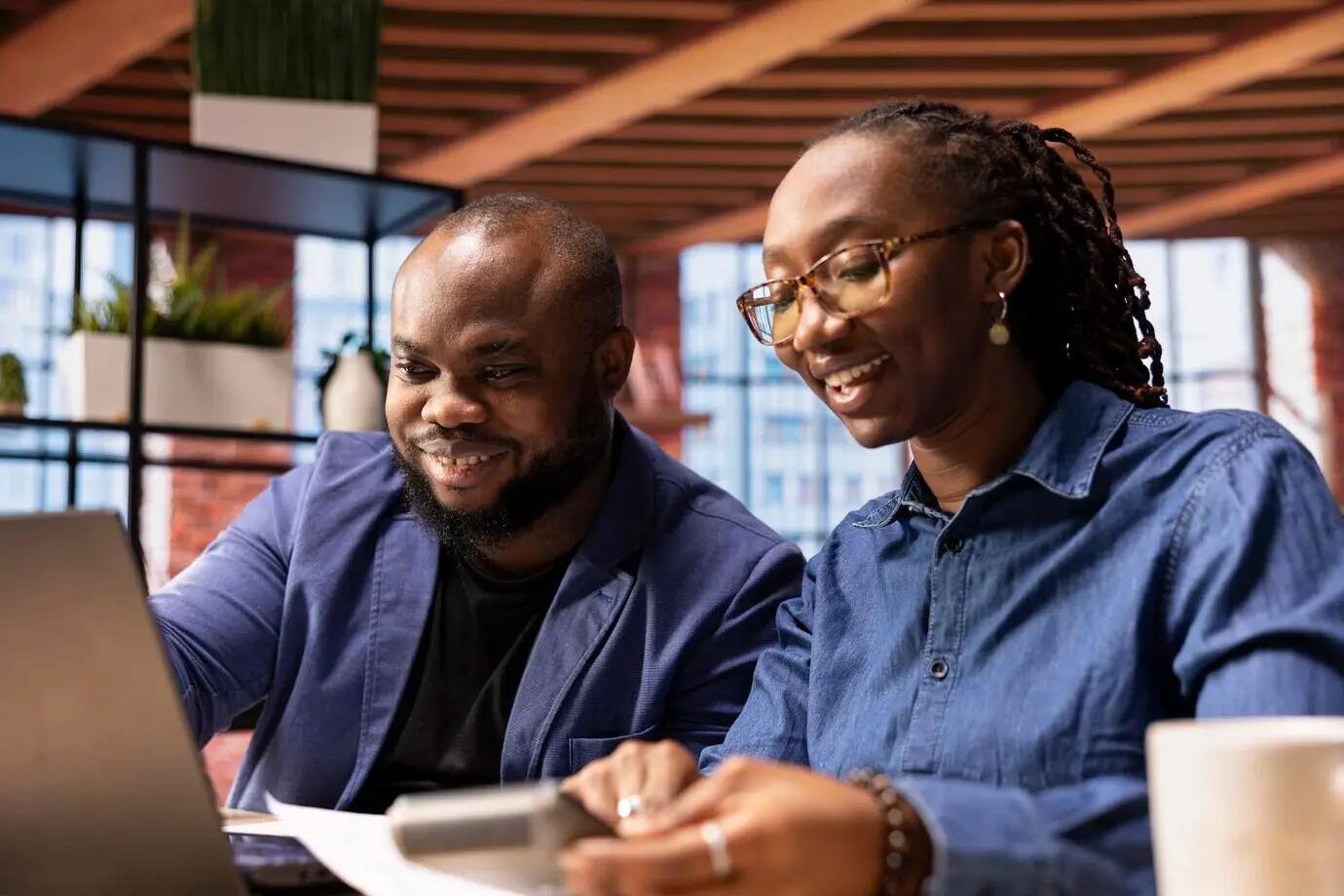 Афроамериканец и афроамериканка просматривают свои отчеты о прибыли и выручке.